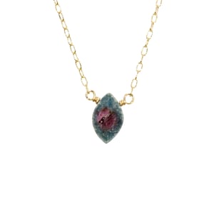 May include: A delicate gold chain necklace with a small, faceted, blue and pink gemstone pendant.