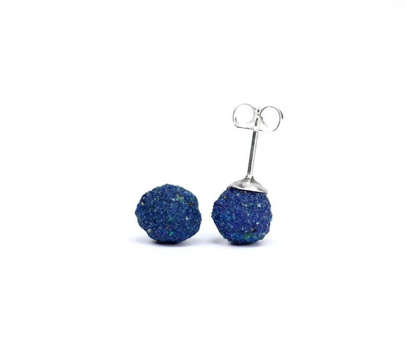 May include: A pair of silver stud earrings with blue azurite stone spheres.