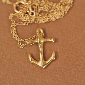 May include: A gold chain necklace with a gold anchor pendant.