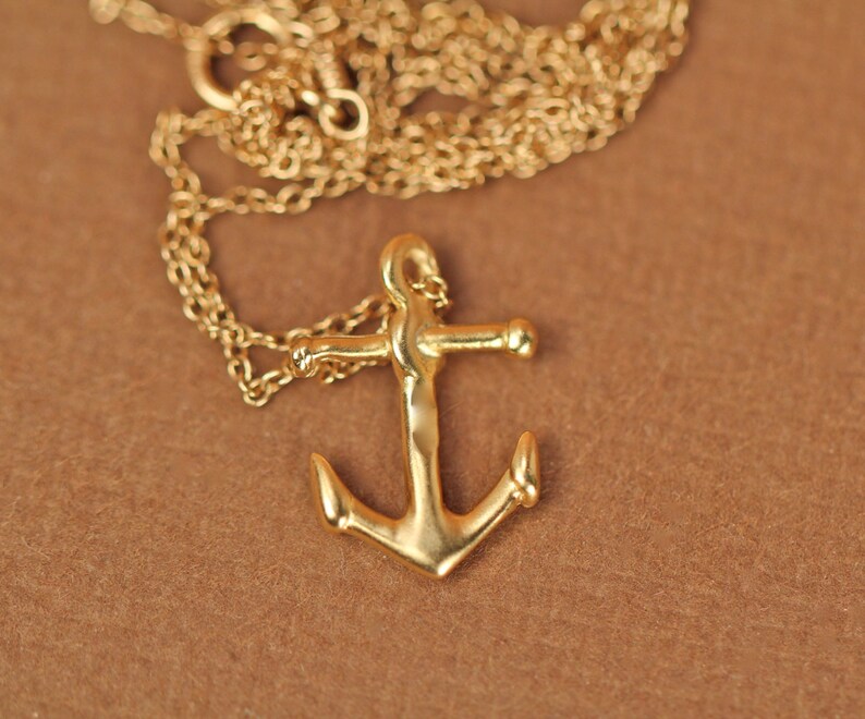 May include: A gold chain necklace with a gold anchor pendant.