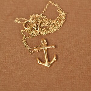May include: A gold anchor pendant necklace with a delicate chain. The anchor is a classic nautical symbol and would make a great gift for a sailor or someone who loves the sea.