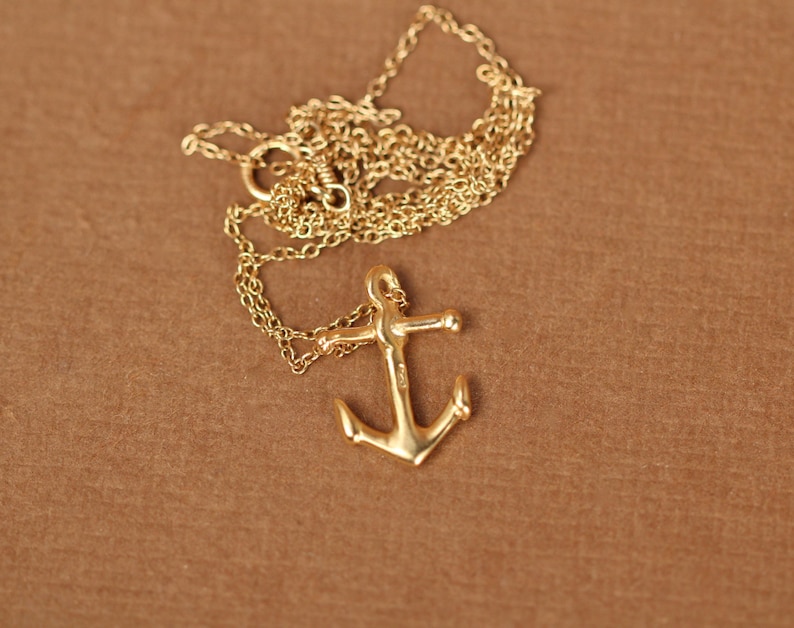 May include: A gold anchor pendant necklace with a delicate chain. The anchor is a classic nautical symbol and would make a great gift for a sailor or someone who loves the sea.