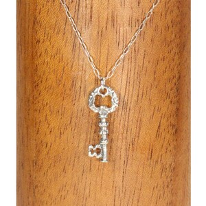 Puede incluir: Un collar con un colgante de llave de plata con un dise&ntilde;o ornamentado. La llave tiene una abertura en forma de coraz&oacute;n y un tallo detallado. El collar est&aacute; en una cadena de plata.