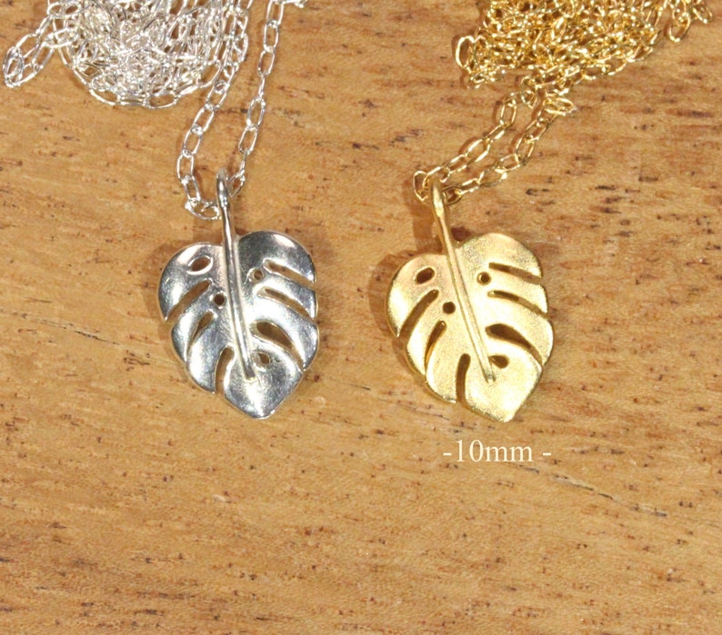 Peut inclure: Deux colliers en argent et en or avec un pendentif en forme de feuille de monstera. La feuille est d&eacute;coup&eacute;e et pr&eacute;sente un design d&eacute;licat. Les colliers mesurent 10 mm de long.