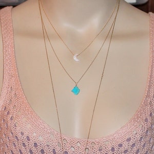 May include: A layered gold necklace with a turquoise stone pendant and a small crescent moon pendant.