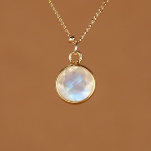 May include: A gold chain necklace with a round, iridescent moonstone pendant.
