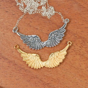 Peut inclure: Deux breloques d'ailes d'ange en argent, l'une sur un collier &agrave; cha&icirc;ne et l'autre sur une cha&icirc;ne s&eacute;par&eacute;e. Les ailes d'ange sont d&eacute;taill&eacute;es et ont une finition textur&eacute;e. Le collier est en argent et a une cha&icirc;ne d&eacute;licate.