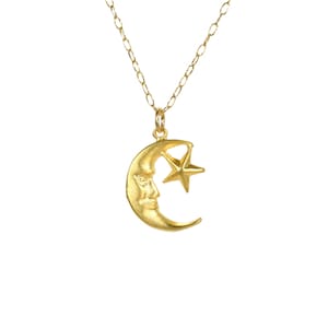 May include: A gold necklace with a crescent moon pendant featuring a face and a small star.
