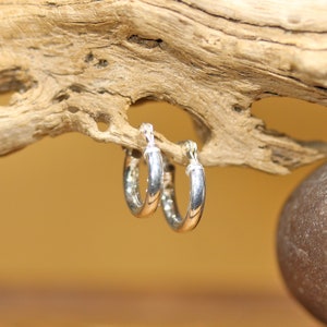 May include: A pair of silver hoop earrings. The earrings are simple and elegant, with a smooth, polished finish.