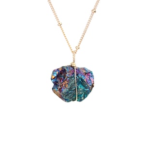 May include: A gold chain necklace with a large, iridescent, blue, purple and red crystal pendant.