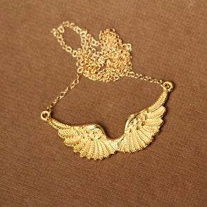 Peut inclure: Un collier en cha&icirc;ne dor&eacute;e avec un pendentif en forme d'ailes d'ange.