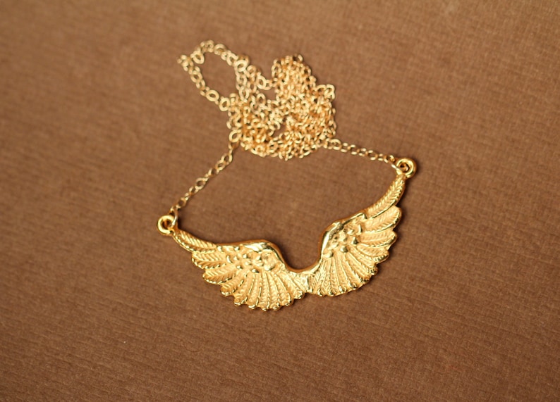 Peut inclure: Un collier en cha&icirc;ne dor&eacute;e avec un pendentif en forme d'ailes d'ange.