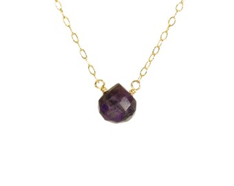 May include: A delicate gold chain necklace with a single, faceted amethyst gemstone pendant.