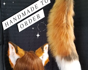 May include: A set of fox ears and a tail, featuring orange, brown, and white faux fur. The ears are attached to a brown wig on a mannequin head. The tail is long and fluffy. Text on the image reads "HANDMADE TO ORDER".