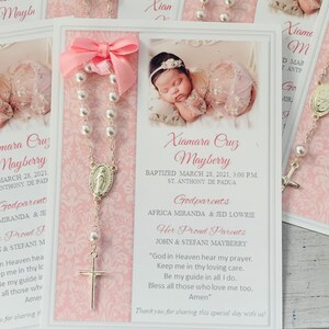 May include: A white card with pink trim and a pink bow. The card has a picture of a baby girl on it. The text on the card reads "Xiamara Cruz Mayberry Baptized March 28, 2021, 3:00 PM. St. Anthony de Padua Godparents Africa Miranda & Jed Lowrie Her Proud Parents John & Stefani Mayberry "God in Heaven hear my prayer. Keep me in thy loving care. Be my guide in all I do. Bless all those who love me too. Amen" Thank you for sharing this special day with us!"