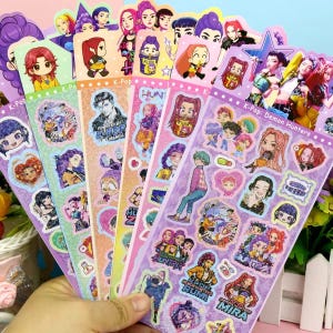 May include: A collection of five vertical sticker sheets featuring colorful anime-style illustrations of characters labeled K-Pop Demon Hunters. The designs include various chibi figures, group portraits, and individual character portraits with text.