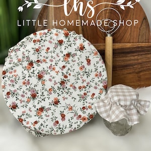 May include: A set of three kitchen items, including a floral patterned bowl cover, a wooden chopping board with a handle, and a dough whisk with a wooden handle. The chopping board has the text "lhs LITTLE HOMEMADE SHOP" on it.