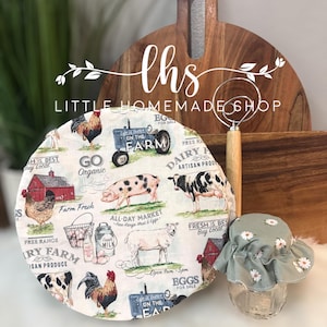 May include: A round, white fabric cover with a farm theme. The cover features illustrations of farm animals, including cows, pigs, chickens, and sheep. The cover also includes text that says "Go Organic", "Farm Fresh", "All Day Market", "Free Range", "Dairy Farm", "Artisan Produce", "Fresh is Best", "Buy Local", and "Life is Better on the Farm".