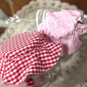 May include: Two fabric jar covers, one red and white gingham and one pink with white hearts. The text "Little Homemade Shop" is visible in the image.