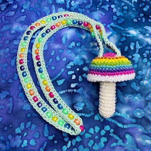 Op de afbeelding: Een gehaakte regenboog paddenstoel bedel met een groene en veelkleurige kralenketting.