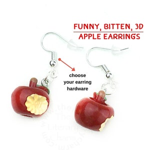 May include: A pair of red 3D apple earrings with a bite taken out of them. The earrings are made of polymer clay and have silver hooks. The text "FUNNY, BITTEN, 3D APPLE EARRINGS" is written above the earrings.
