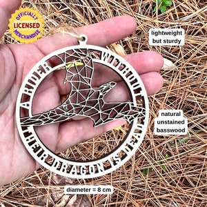geometric dragon laser cut wood ornament held on palm of hand for scale