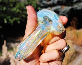 May include: A clear glass pipe with iridescent detailing. The pipe has a round bowl and a long, curved stem.