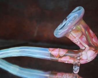 May include: A glass pipe with a pink, white, and blue swirl design. The pipe has a long, curved stem and a bowl at the top.