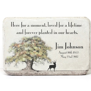 May include: A white rectangular memorial plaque with a quote about being loved for a lifetime and a drawing of a tree and a deer. The plaque reads "Here for a moment, loved for a lifetime and forever planted in our hearts."  The name "Jim Johnson" is printed below the quote, along with the dates "August 10th 1952 - May 22nd 2017".