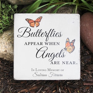 May include: A square, white memorial stone with the text "Butterflies appear when Angels are near." Two orange and black butterflies are printed on the stone. The stone is inscribed "In Loving Memory of Sabrina Ferrara."