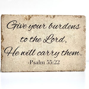 May include: A beige stone block with the text "Give your burdens to the Lord, He will carry them. - Psalm 55:22" in black cursive lettering.