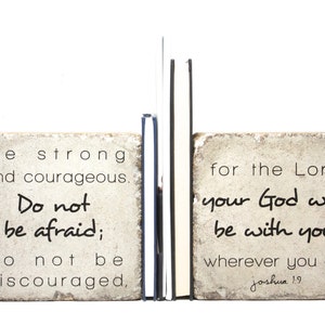 May include: A pair of bookends made of stone with a white background. The left bookend has the text "Be strong and courageous. Do not be afraid; do not be discouraged." The right bookend has the text "for the Lord your God will be with you wherever you go. Joshua 1.9".