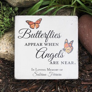 May include: A square, off-white memorial stone with the text "Butterflies appear when Angels are near." Two orange and black butterflies are printed on the stone. The text "In Loving Memory of Sabrina Ferrara" is also printed on the stone.