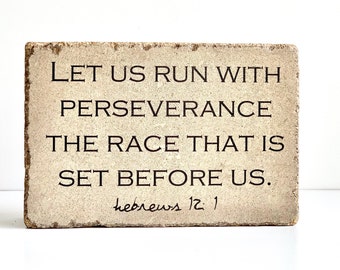 May include: A beige stone block with the text "LET US RUN WITH PERSEVERANCE THE RACE THAT IS SET BEFORE US." and "hebrews 12:1" in black lettering.