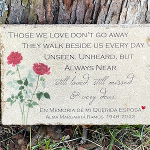 May include: A stone memorial plaque with a floral design and the text "Those we love don't go away. They walk beside us every day. Unseen, unheard, but always near. Still loved, still missed & very dear. En memoria de mi querida esposa Alma Margarita Ramos 1948-2022"