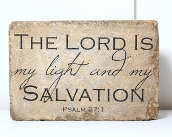 May include: A beige stone plaque with black lettering that reads "THE LORD IS my light and my SALVATION -PSALM 27:1".