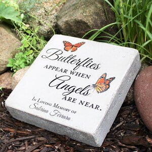 May include: A rectangular, light gray memorial stone with the text "Butterflies Appear When Angels Are Near." Two orange butterflies are depicted. The inscription reads "In Loving Memory of Sabrina Ferrara."