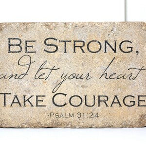 May include: A beige stone plaque with the text "Be strong, and let your heart take courage - Psalm 31:24" in black lettering.