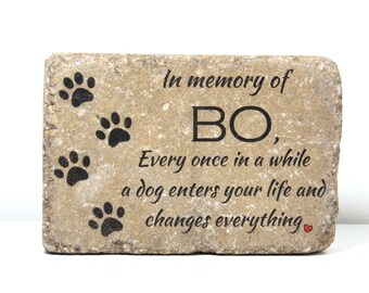 May include: A stone memorial with paw prints and the text "In memory of BO, Every once in a while a dog enters your life and changes everything."