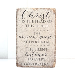 May include: A rustic wooden sign with the text "Christ is the head of this house. The unseen guest at every meal. The silent listener to every conversation."