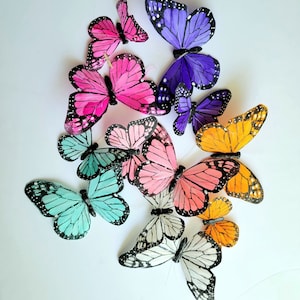May include: A collection of colourful butterfly decorations with various wing patterns and colours, including pink, purple, blue, orange, and white.