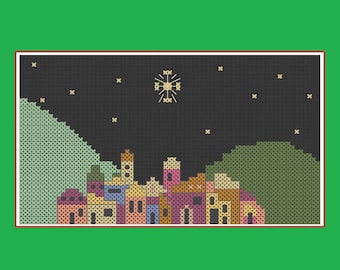 Peut inclure: Broderie au point de croix représentant un village sous un ciel étoilé. Les bâtiments sont de différentes couleurs, avec une grande étoile au-dessus. Des collines vertes encadrent le village, le tout sur un fond bleu foncé.