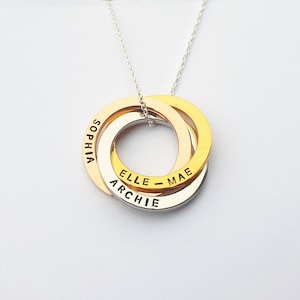 May include: A gold, silver and rose gold interlocking circle necklace with the names "Sophia", "Archie", and "Elle - Mae" engraved on the rings.