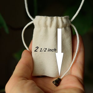 May include: A small white drawstring bag with a 2 1/2 inch diameter. The bag is made of natural cotton fabric and has a simple design.