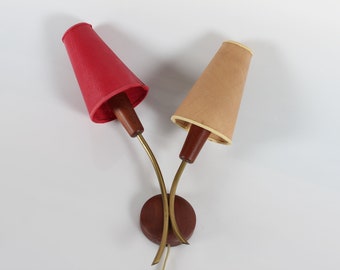Puede incluir: Un par de apliques de pared vintage con brazos curvos de latón y bases de madera. Las pantallas son rojas y beige.