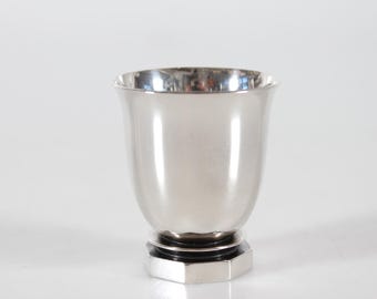 May include: A silver goblet with a black base. The goblet has a rounded, bell-shaped bowl and a hexagonal base.