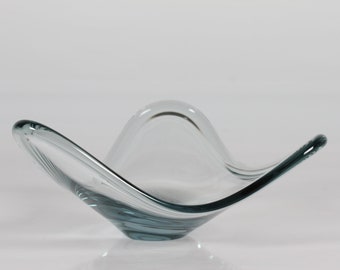 May include: A clear glass bowl with a wavy, organic shape. The bowl has a light blue tint and is perfect for serving snacks or fruit.