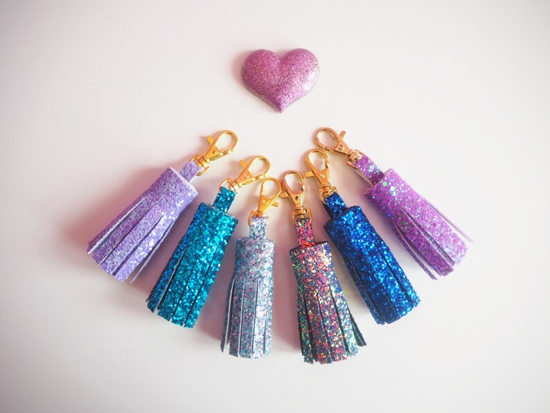 May include: Six sparkly keychains with gold clasps. The keychains are in shades of purple, blue, and teal.