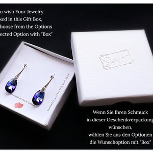 Pu&ograve; includere: Una scatola regalo bianca con un paio di orecchini a goccia viola all'interno. La scatola ha il testo "If You wish Your Jewelry packed in this Gift Box, please Choose from the Options Your selected Option with "Box"" in alto e il testo "Wenn Sie Ihren Schmuck in dieser Geschenkverpackung w&uuml;nschen, w&auml;hlen Sie aus den Optionen die Wunschoption mit "Box"" in basso.