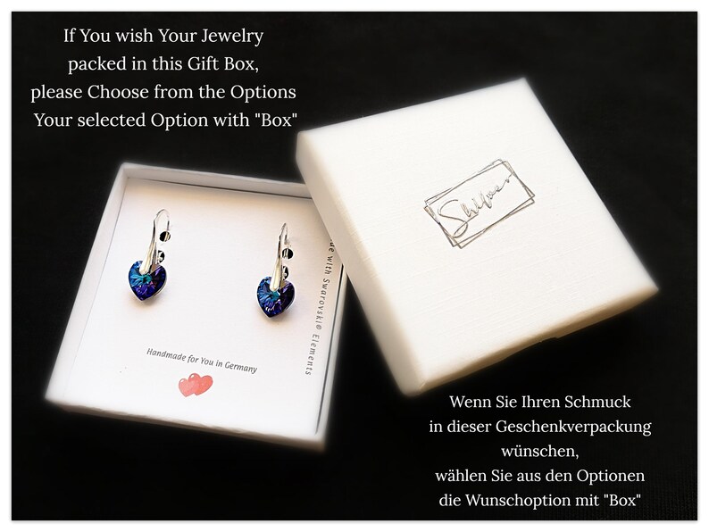 May include: A white gift box with a pair of silver heart-shaped earrings with blue and purple crystals. The box has the text "If You wish Your Jewelry packed in this Gift Box, please Choose from the Options Your selected Option with "Box" Handmade for You in Germany" printed on it. The box also has the text "Shiyoun" printed on it.